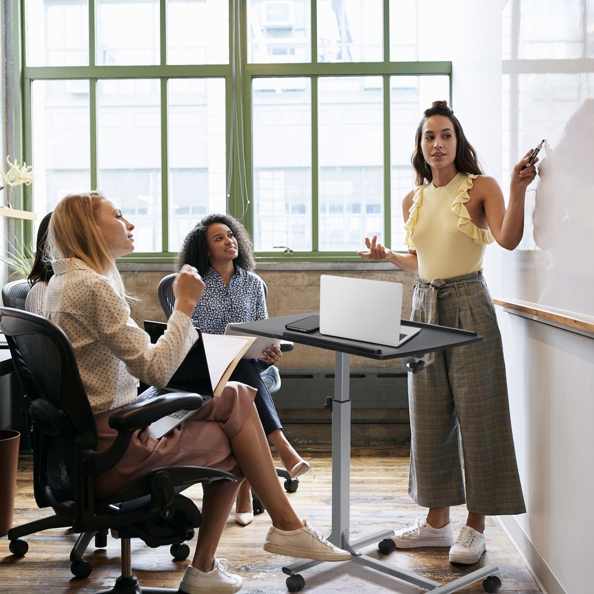 Two colleagues reviewing notes beside a standing desk in an open office